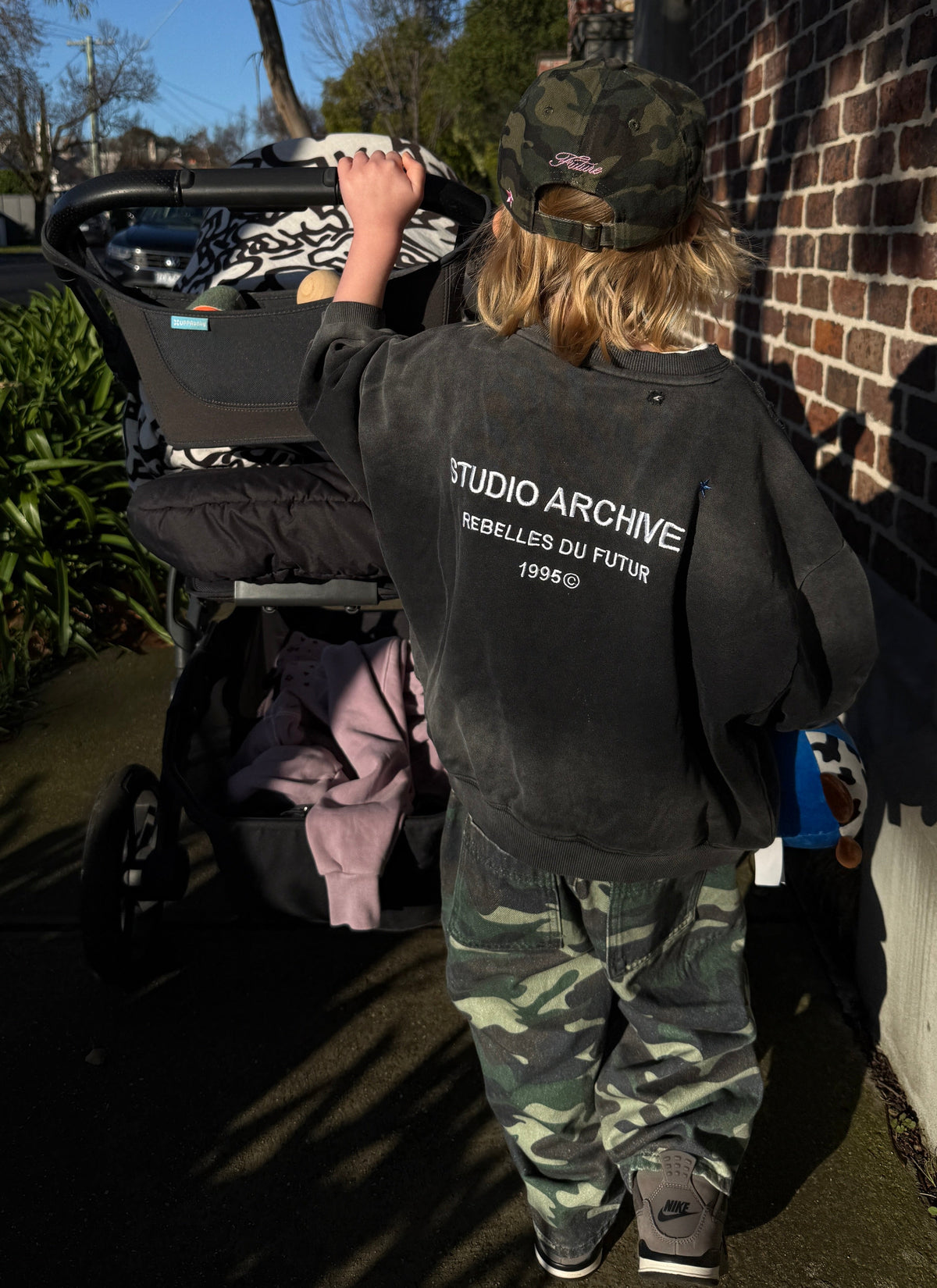 A child viewed from behind wearing a black graphic sweatshirt with &